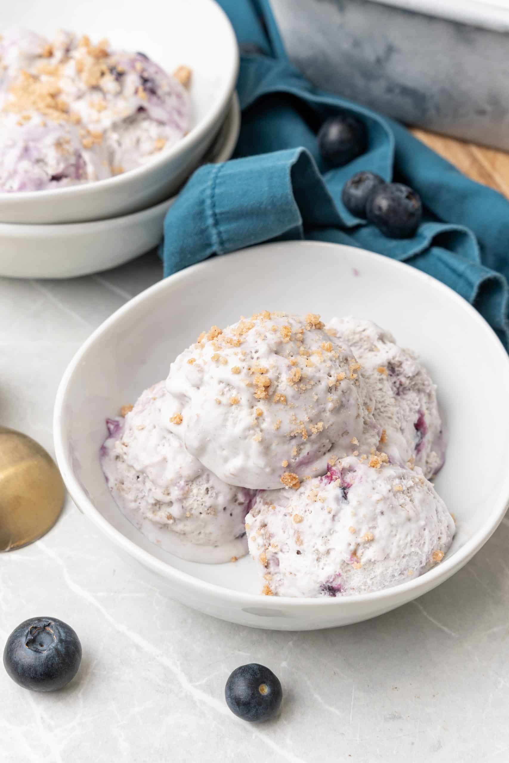 three scoops of no churn blueberry muffin ice cream in a white bowl