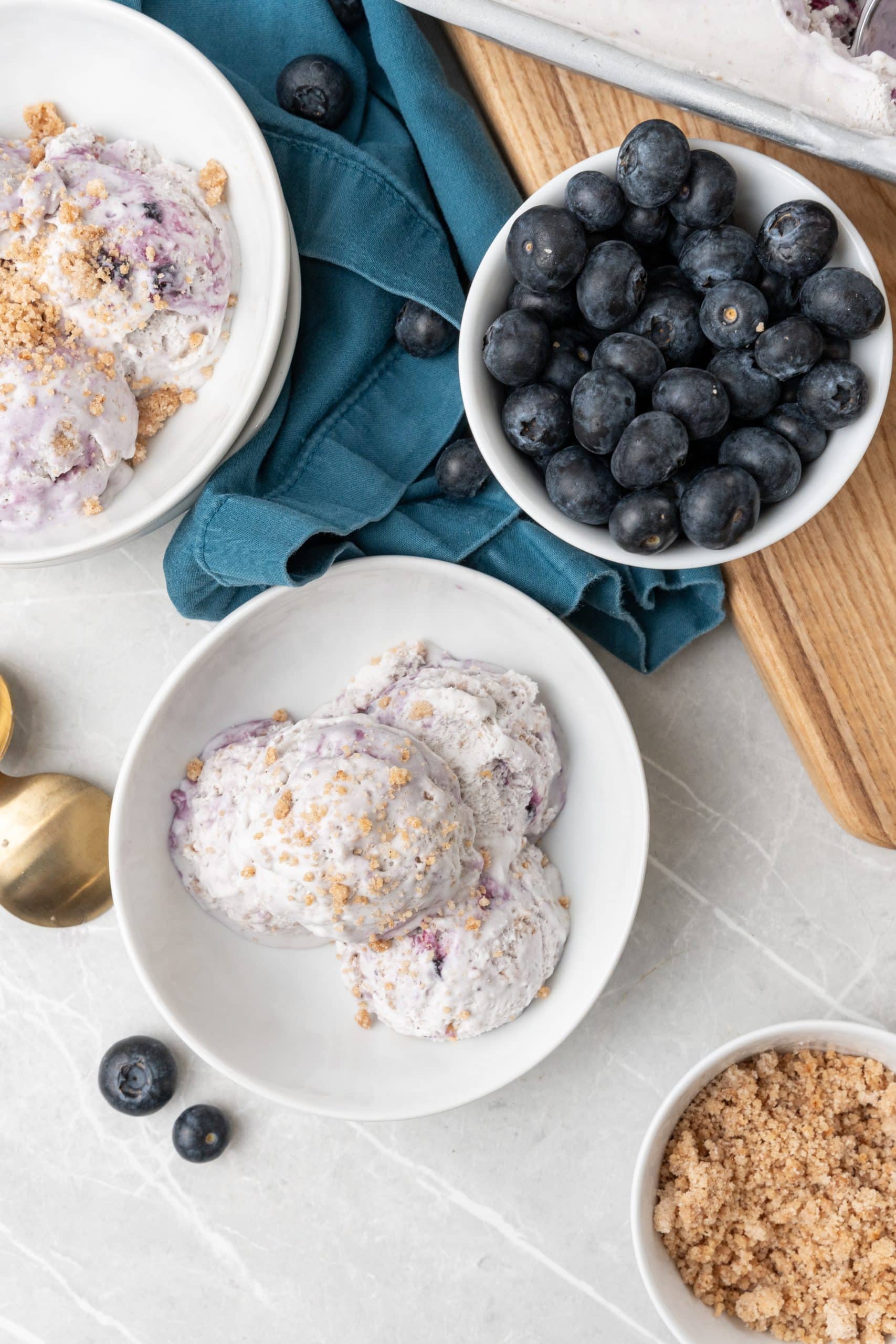 three scoops of no churn blueberry muffin ice cream in a two white bowls