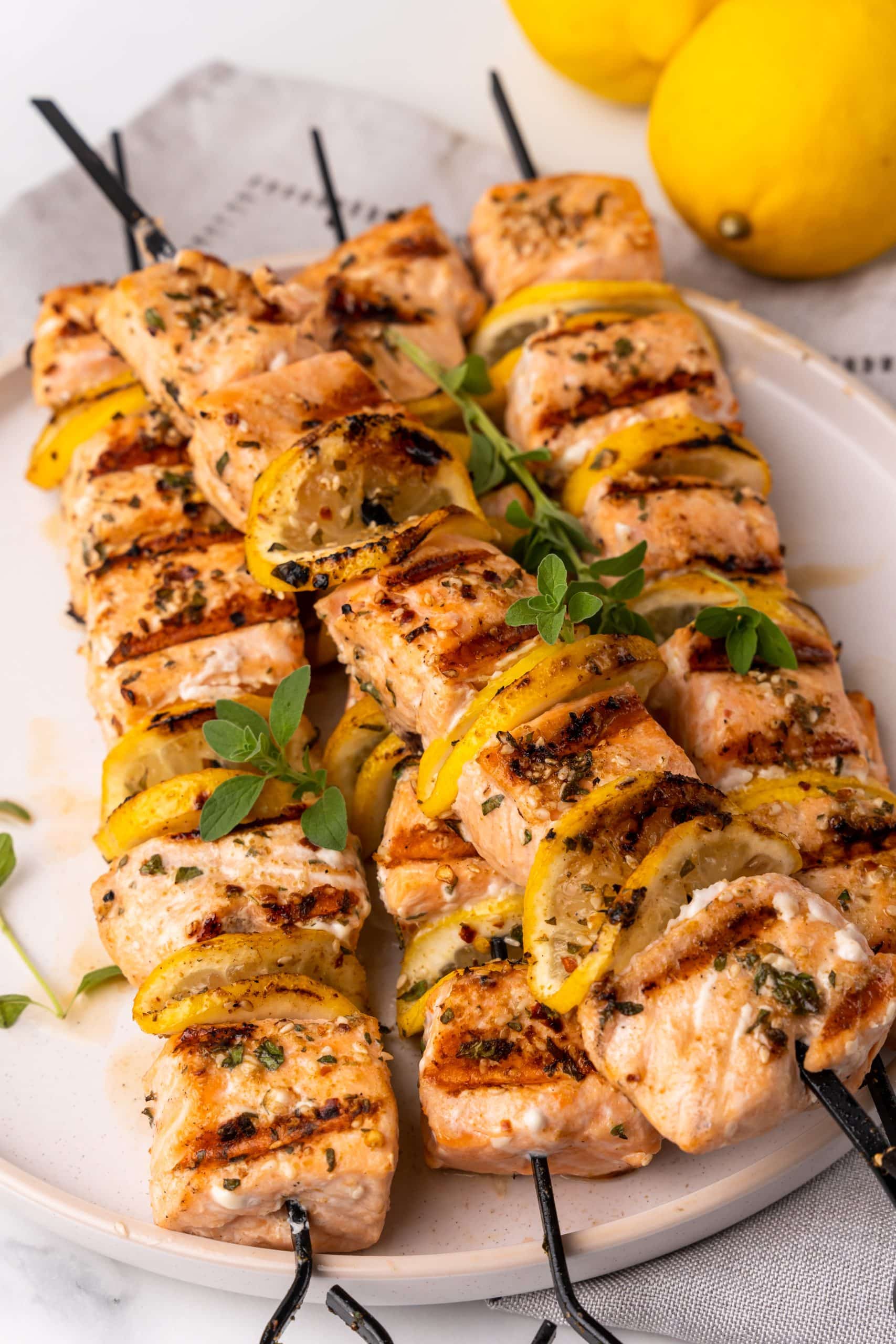 lemon herb grilled salmon kebabs stacked on a white plate
