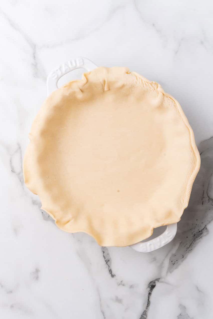 an unbaked pie crust in a white pie plate