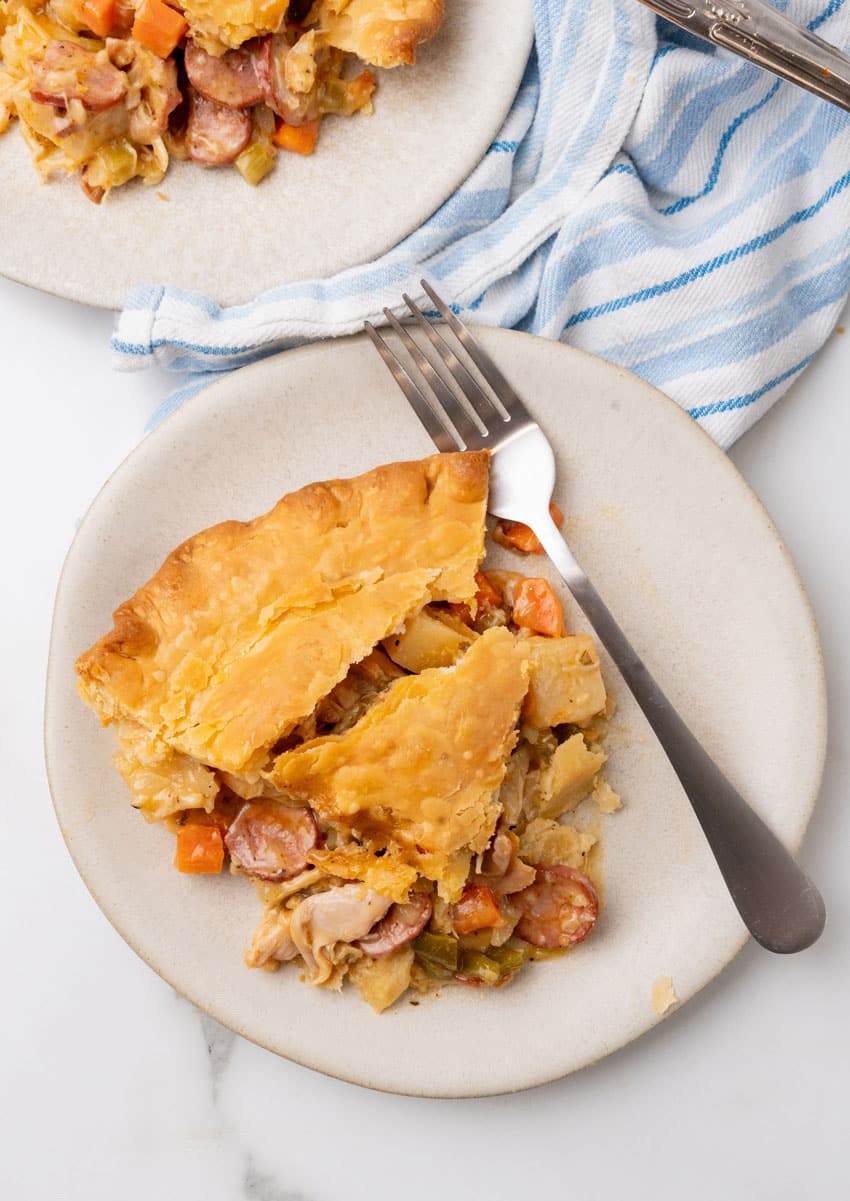 a slice of smoked sausage and chicken pot pie on a small white plate