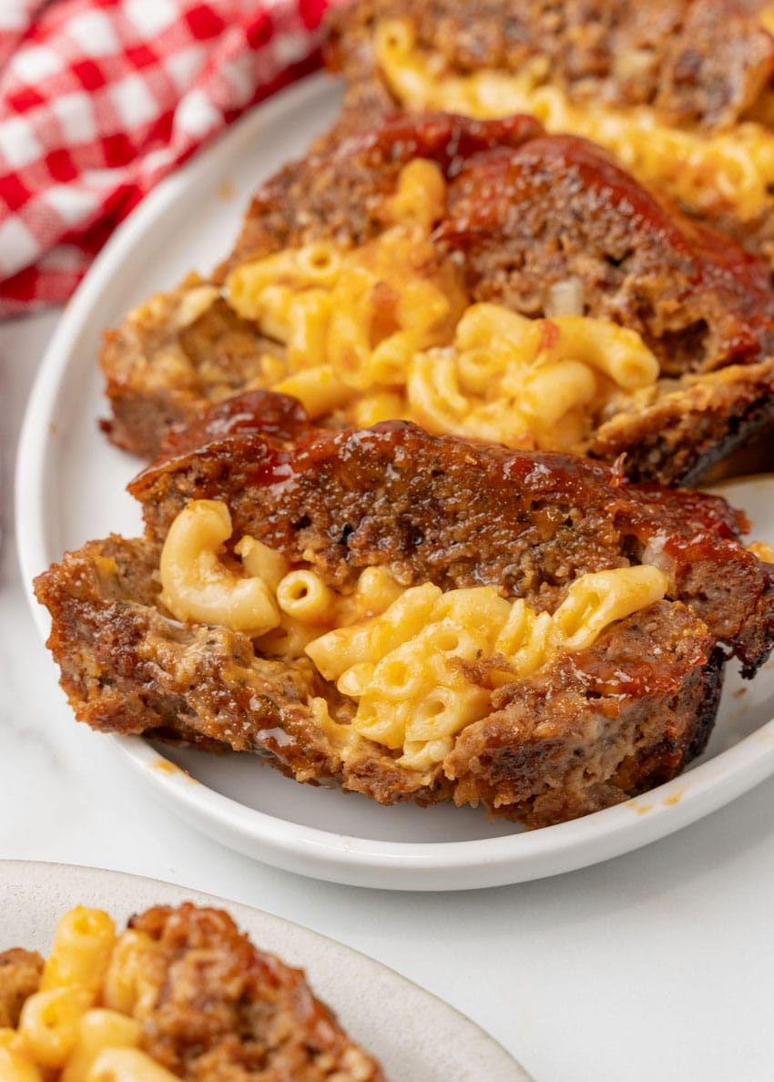 SLICES OF MAC AND CHEESE STUFFED MEATLOAF ARRANGED IN A ROW ON A WHITE SERVING PLATTER