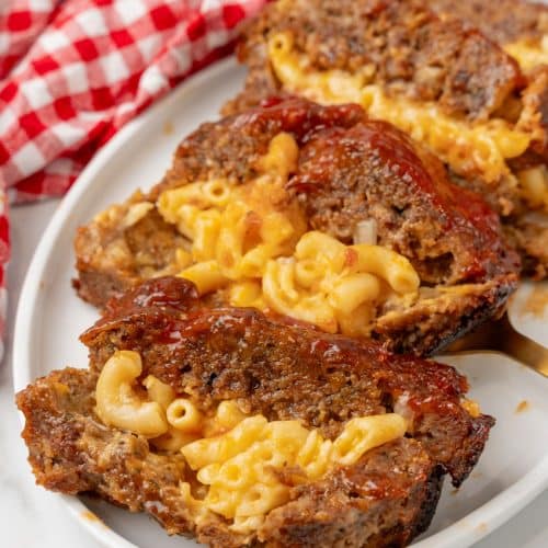 SLICES OF MAC AND CHEESE STUFFED MEATLOAF ARRANGED IN A ROW ON A WHITE SERVING PLATTER