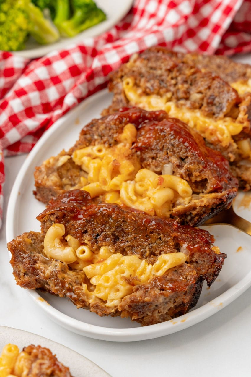 SLICES OF MAC AND CHEESE STUFFED MEATLOAF ARRANGED IN A ROW ON A WHITE SERVING PLATTER