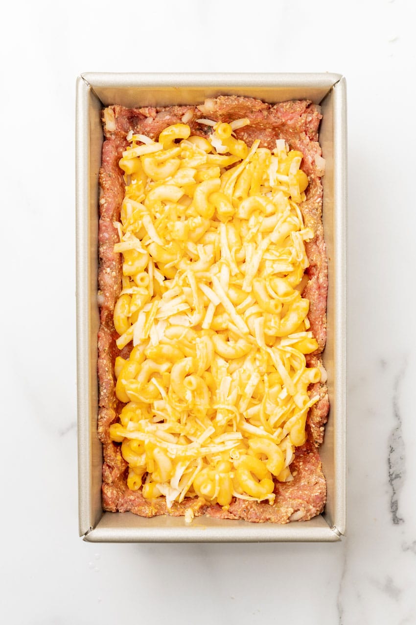 mac and cheese topped seasoned ground beef in a metal loaf pan