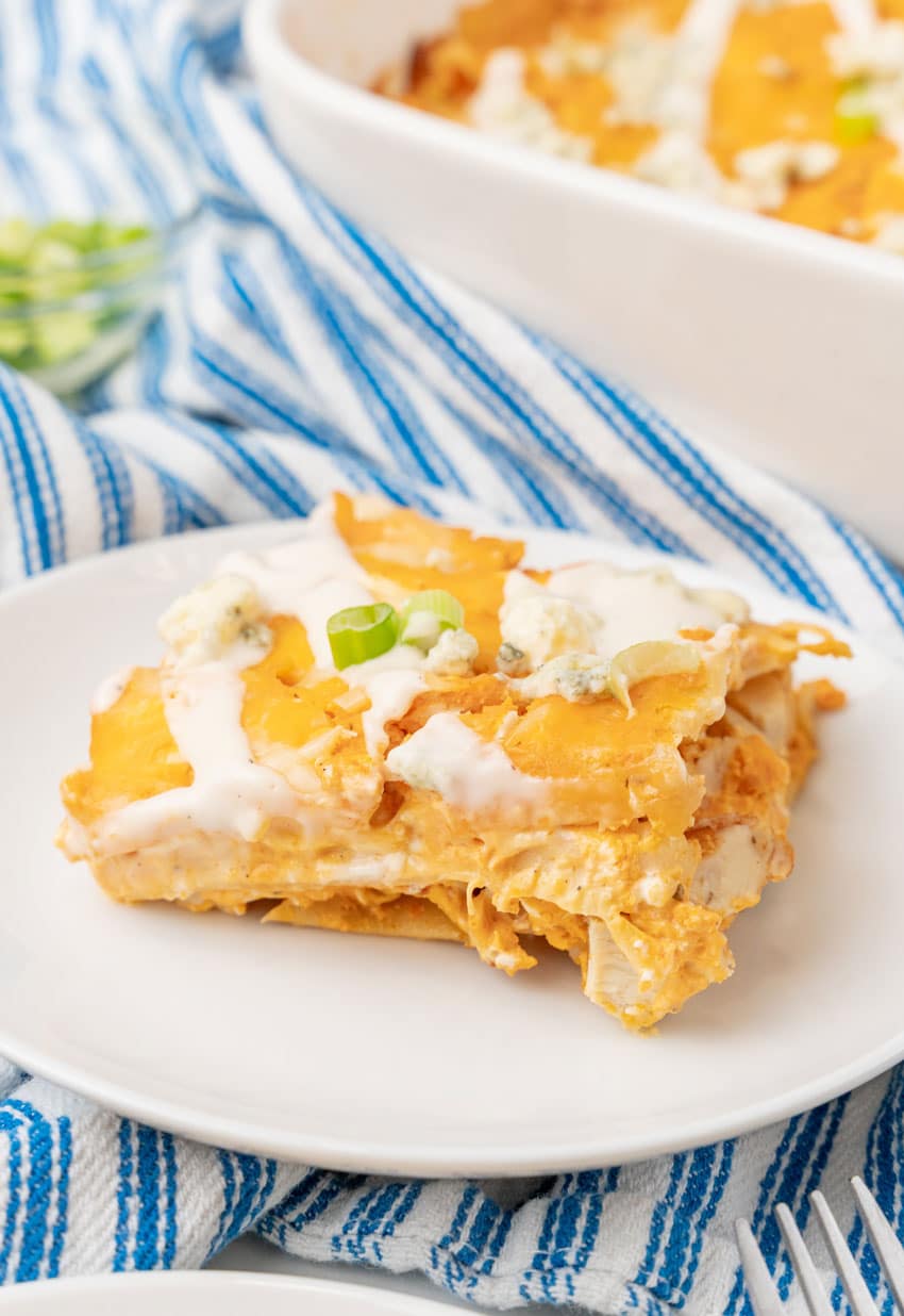 a close up of a slice of cheesy buffalo chicken lasagna on a small white dinner plate