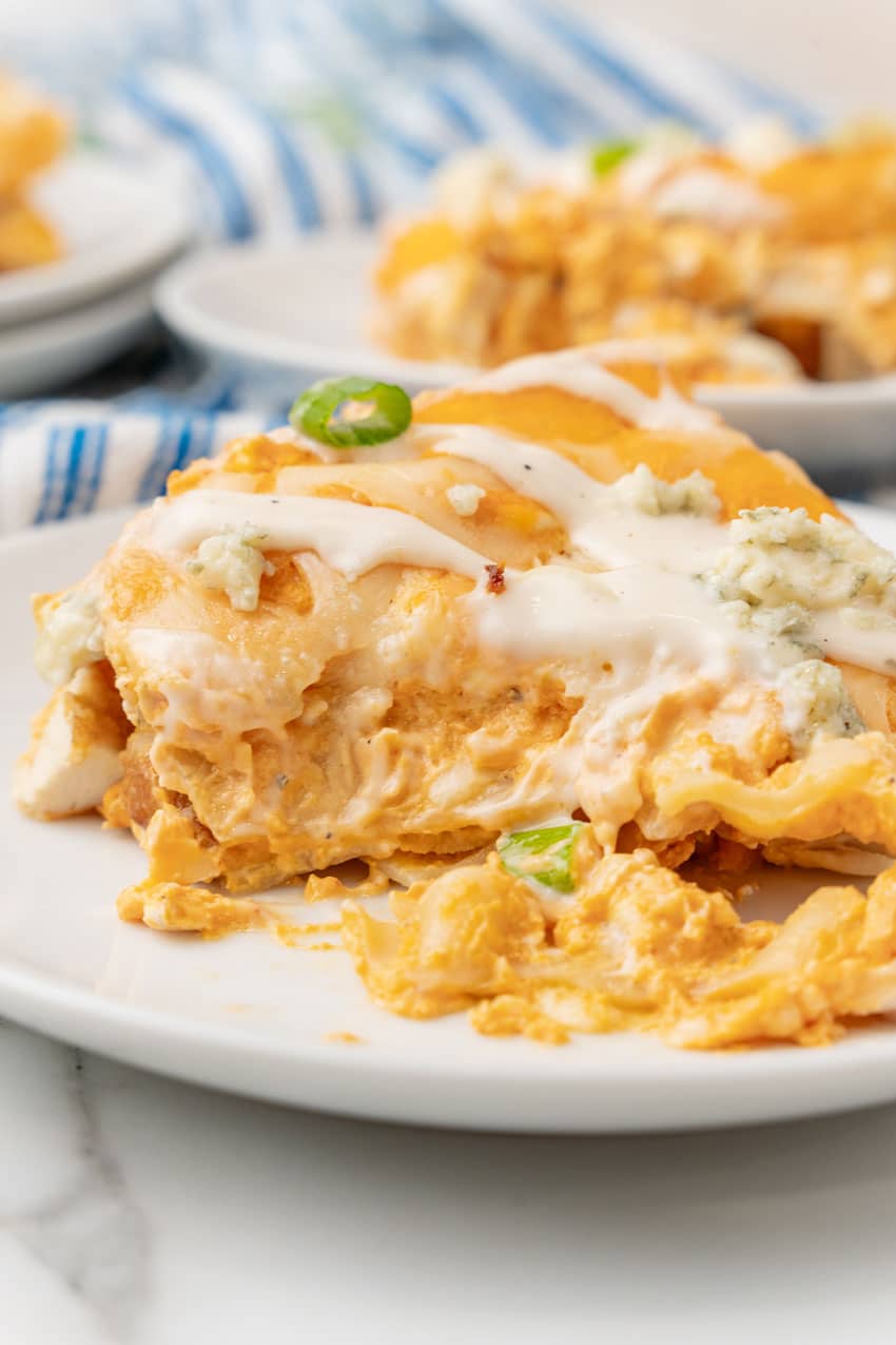 a close up of a slice of cheesy buffalo chicken lasagna on a small white dinner plate