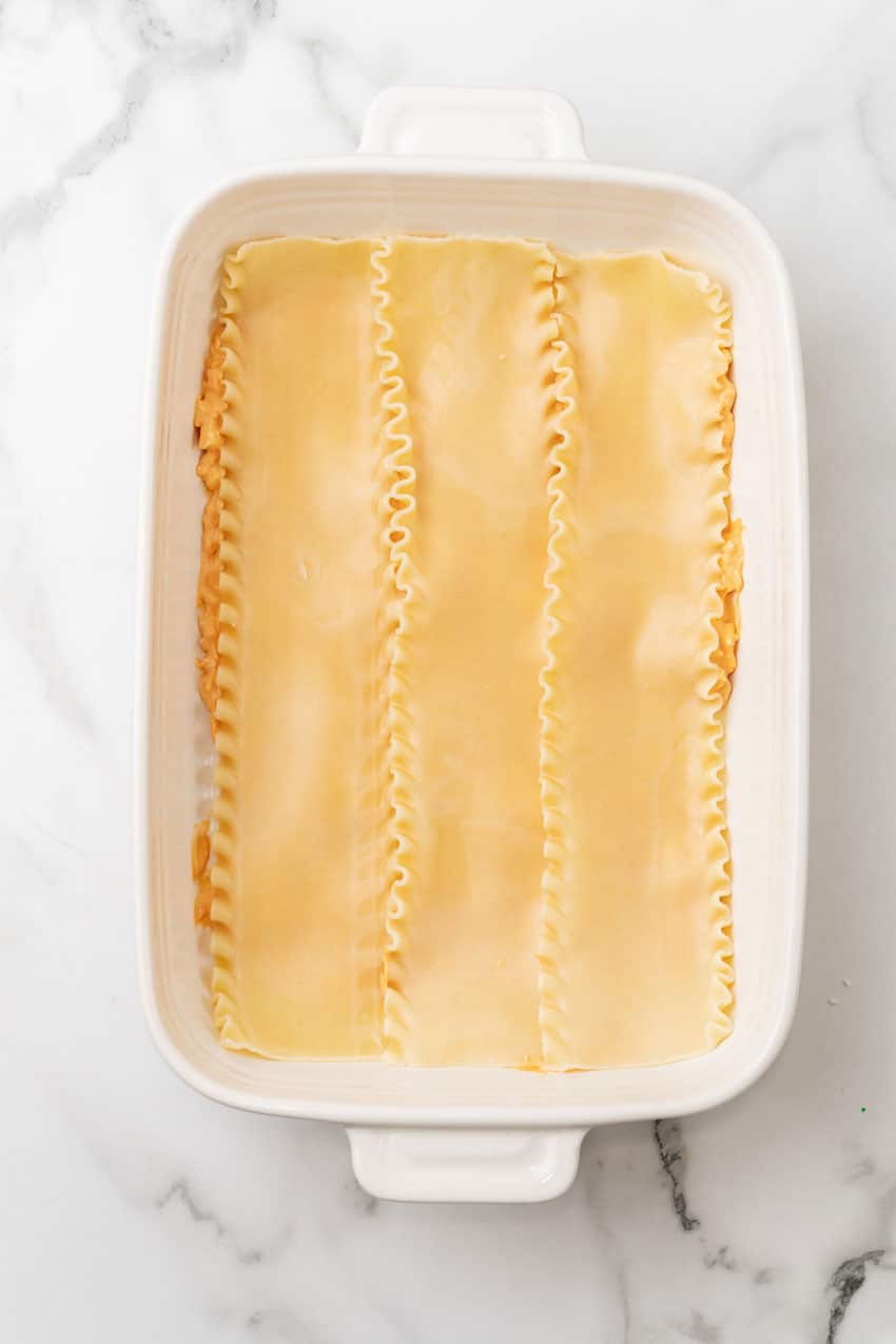 a layer of buffalo chicken lasagna in a white baking dish