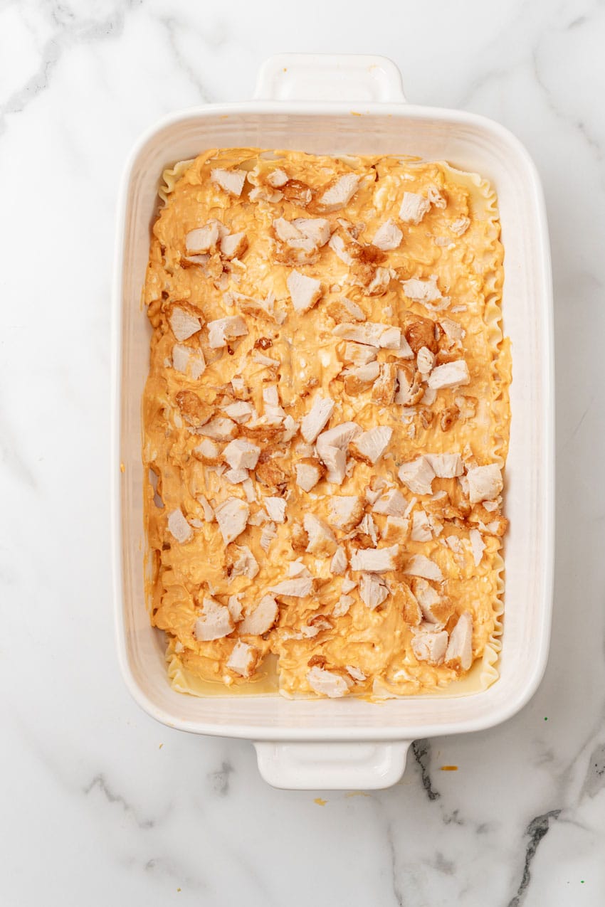 a layer of buffalo chicken lasagna in a white baking dish