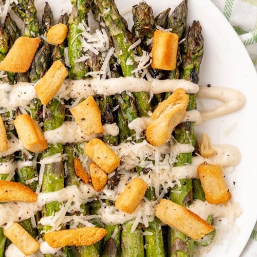 caesar style grilled asparagus on a white serving plate