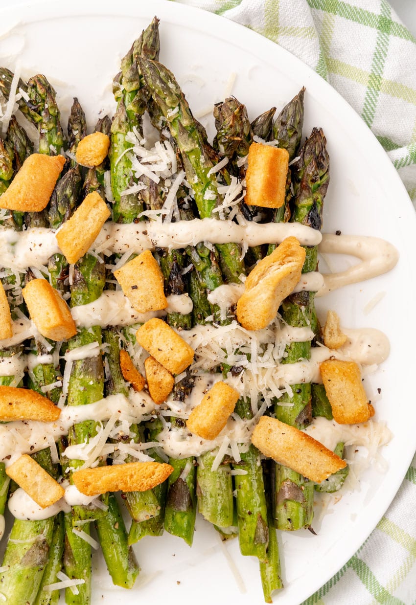 caesar style grilled asparagus on a white serving plate