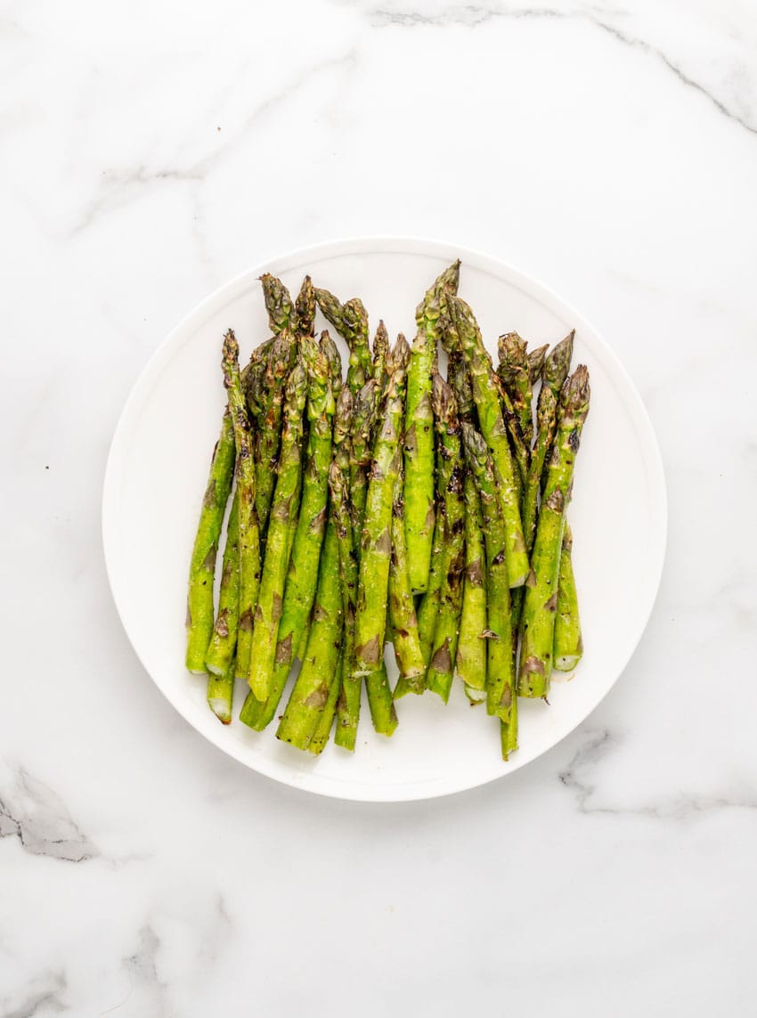 grilled asparagus spears on a white serving plate
