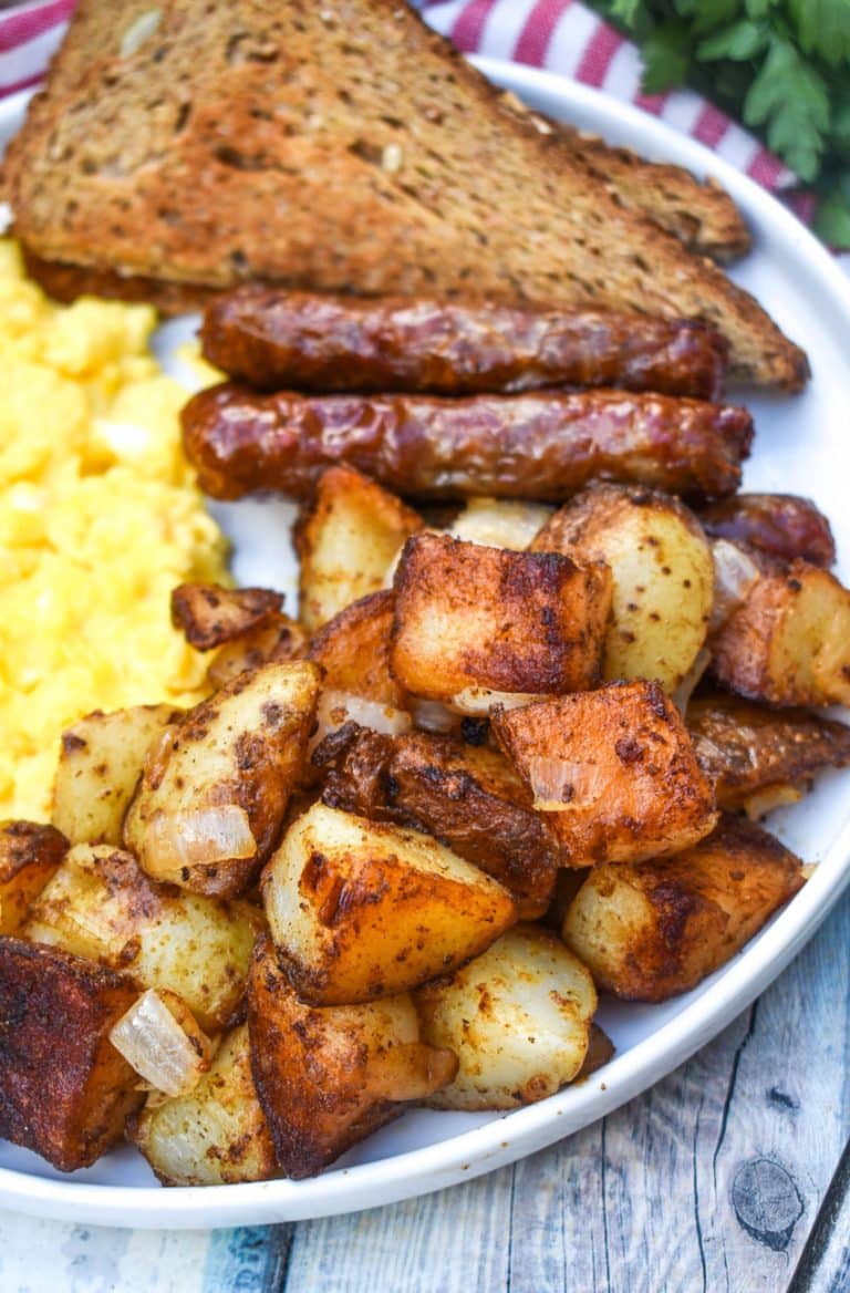 DINER STYLE HOME FRIED BREAKFAST POTATOES ON A WHITE PLATE ALONG WITH SCRAMBLED EGGS, SAUSAGE LINKS, AND TOAST