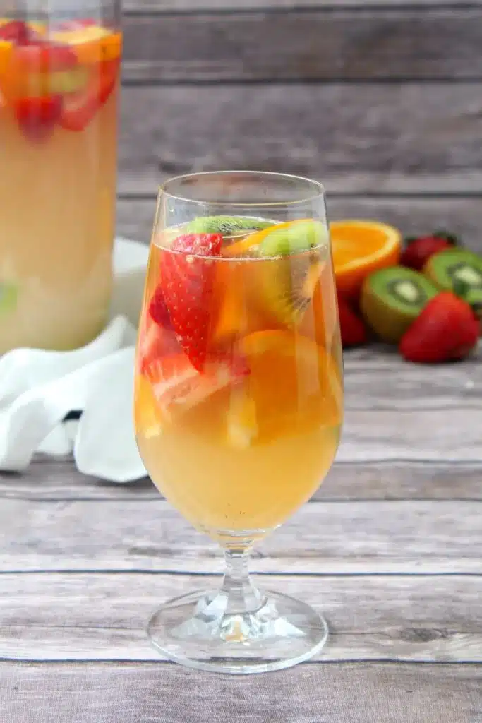 A GLASS OF TROPICAL WHITE WINE SANGRIA ON A WOODEN TABLE