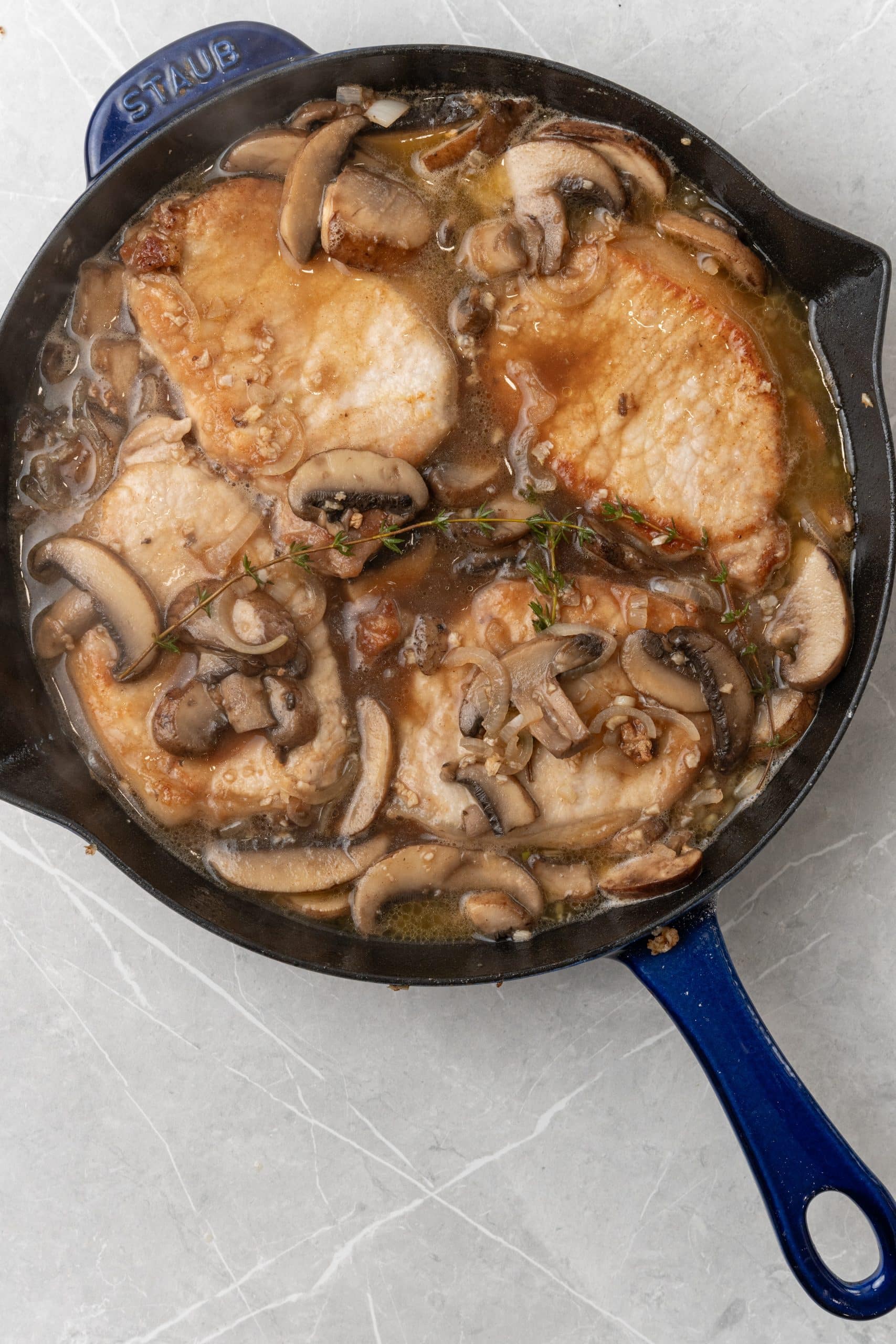 braised pork marsala with mushrooms and onion in a cast iron skillet