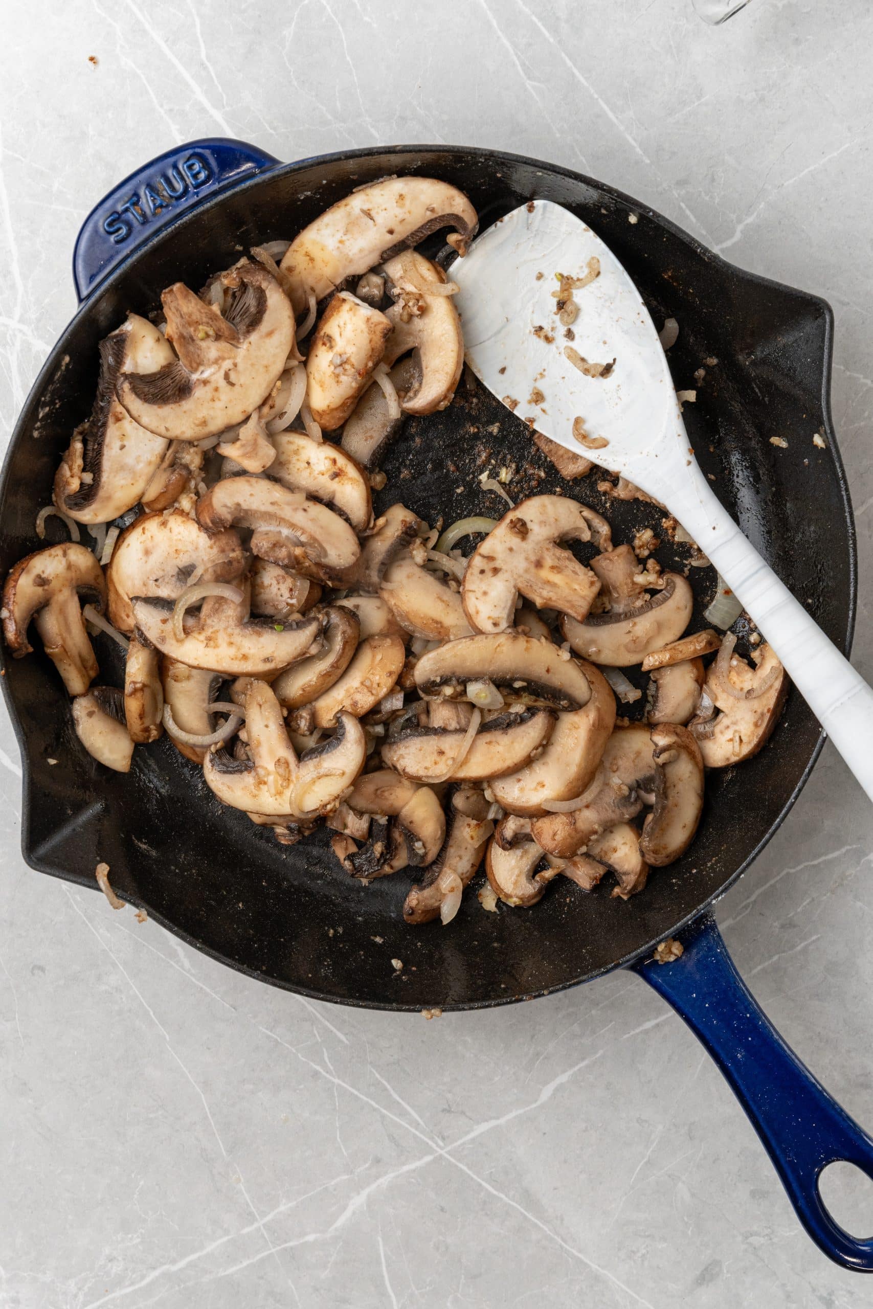 sliced onions and mushrooms cooking in butter in a cast iron skillet