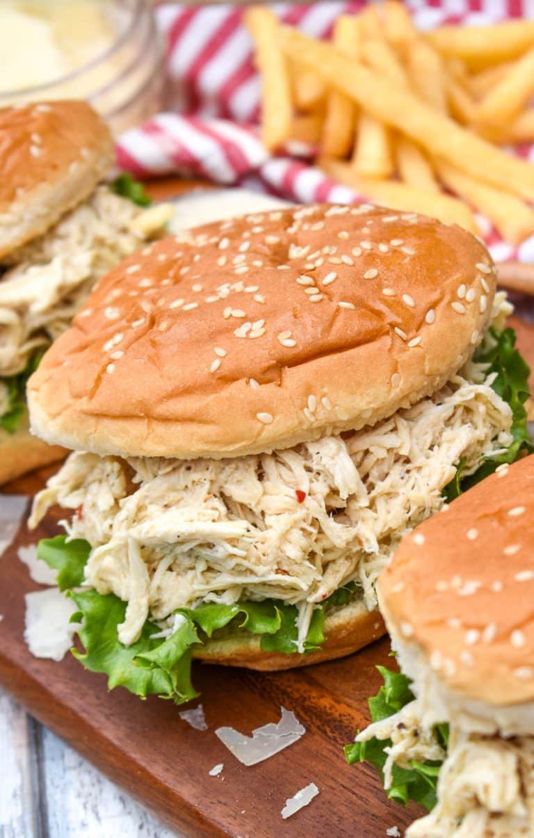 easy crock pot chicken caesar sandwiches on a wooden cutting board