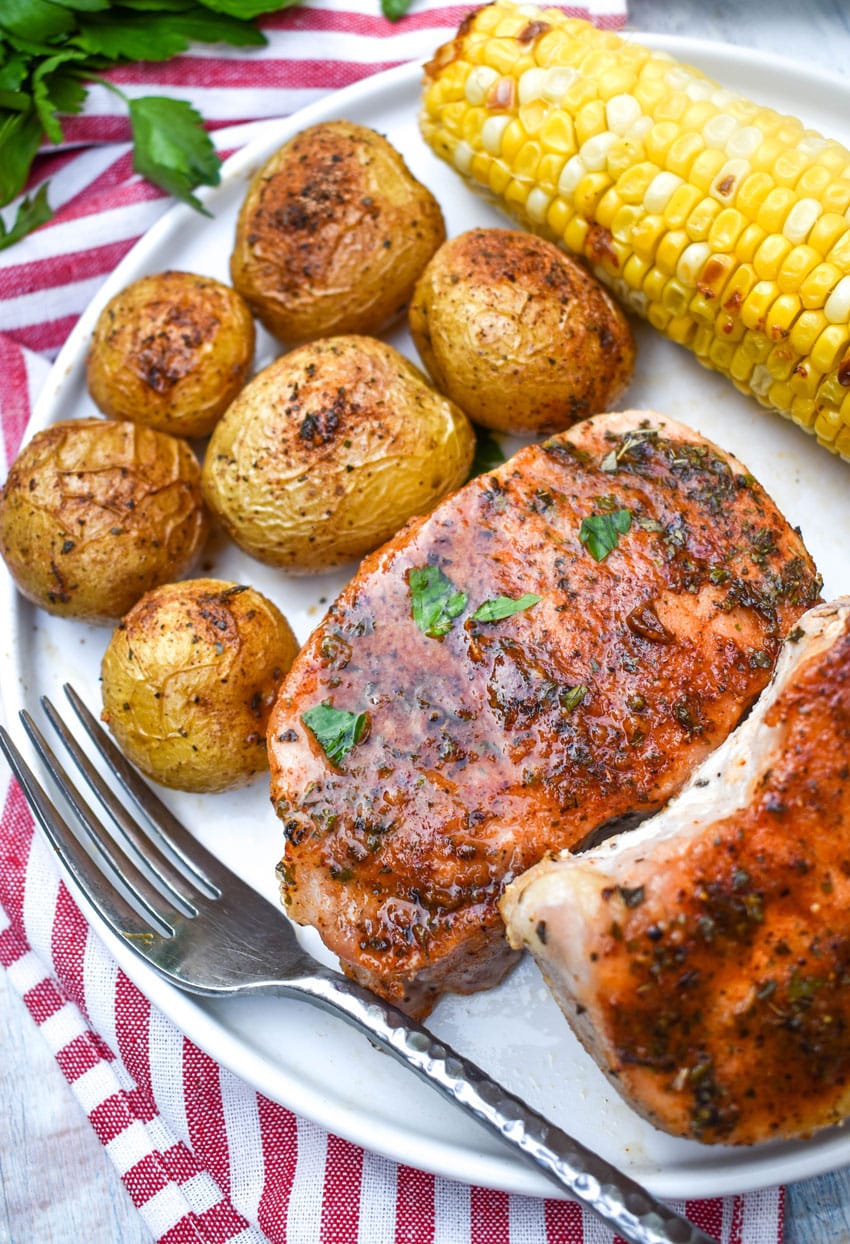 ranch pork chops with seasoned potatoes and a piece of corn on the cob on a white dinner plate