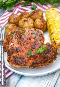 ranch pork chops with seasoned potatoes and a piece of corn on the cob on a white dinner plate