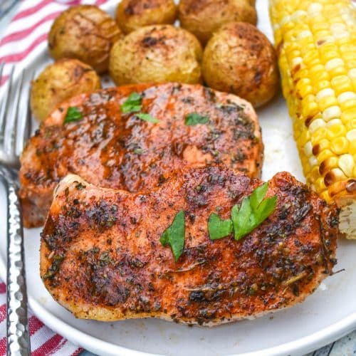 ranch pork chops with seasoned potatoes and a piece of corn on the cob on a white dinner plate