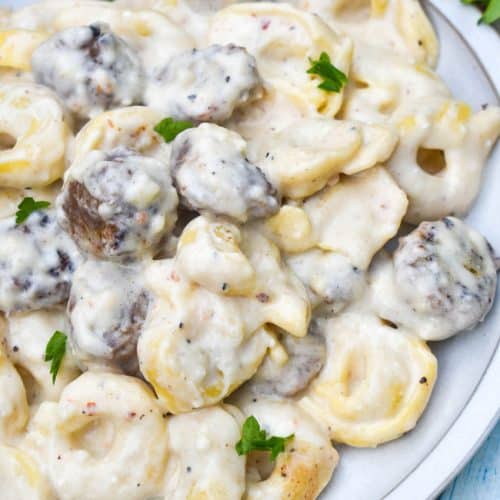 sausage tortellini alfredo on a white plate