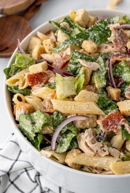 chicken caesar pasta salad in a large white mixing bowl