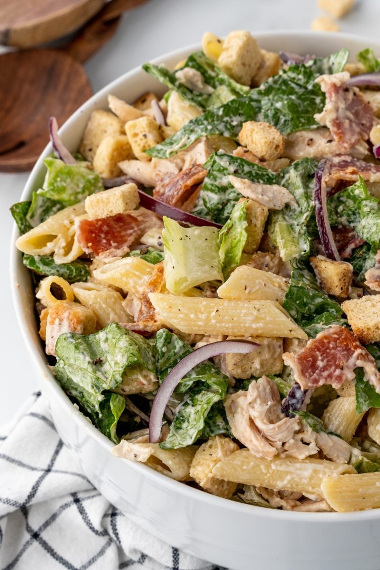 chicken caesar pasta salad in a large white mixing bowl