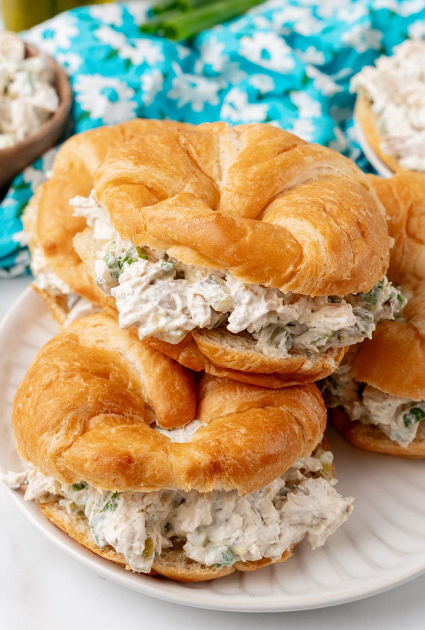 dill pickle chicken salad in croissant roll sandwiches stacked on a white plate