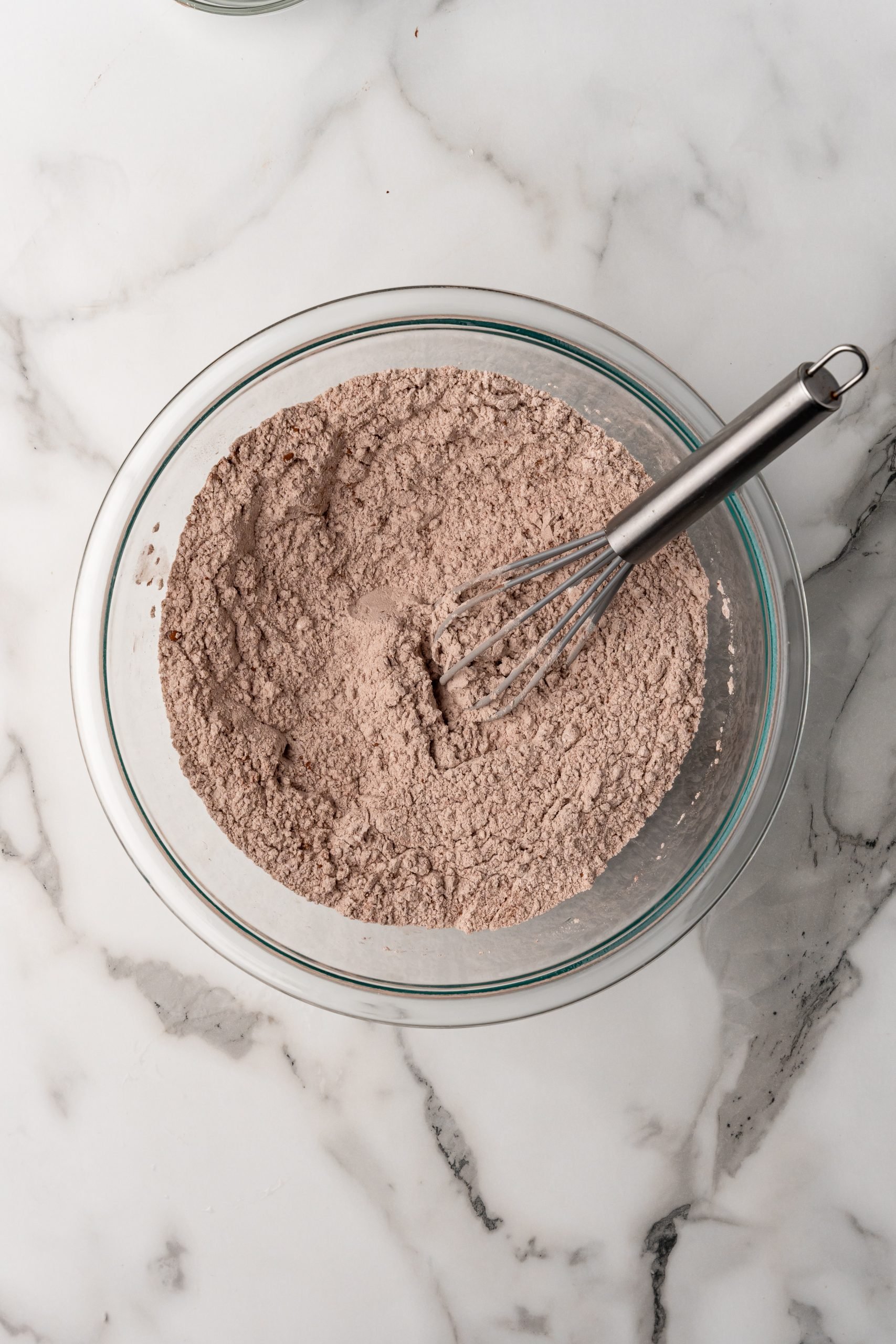 flour and cocoa powder mixed in a glass mixing bowl with a wire whisk