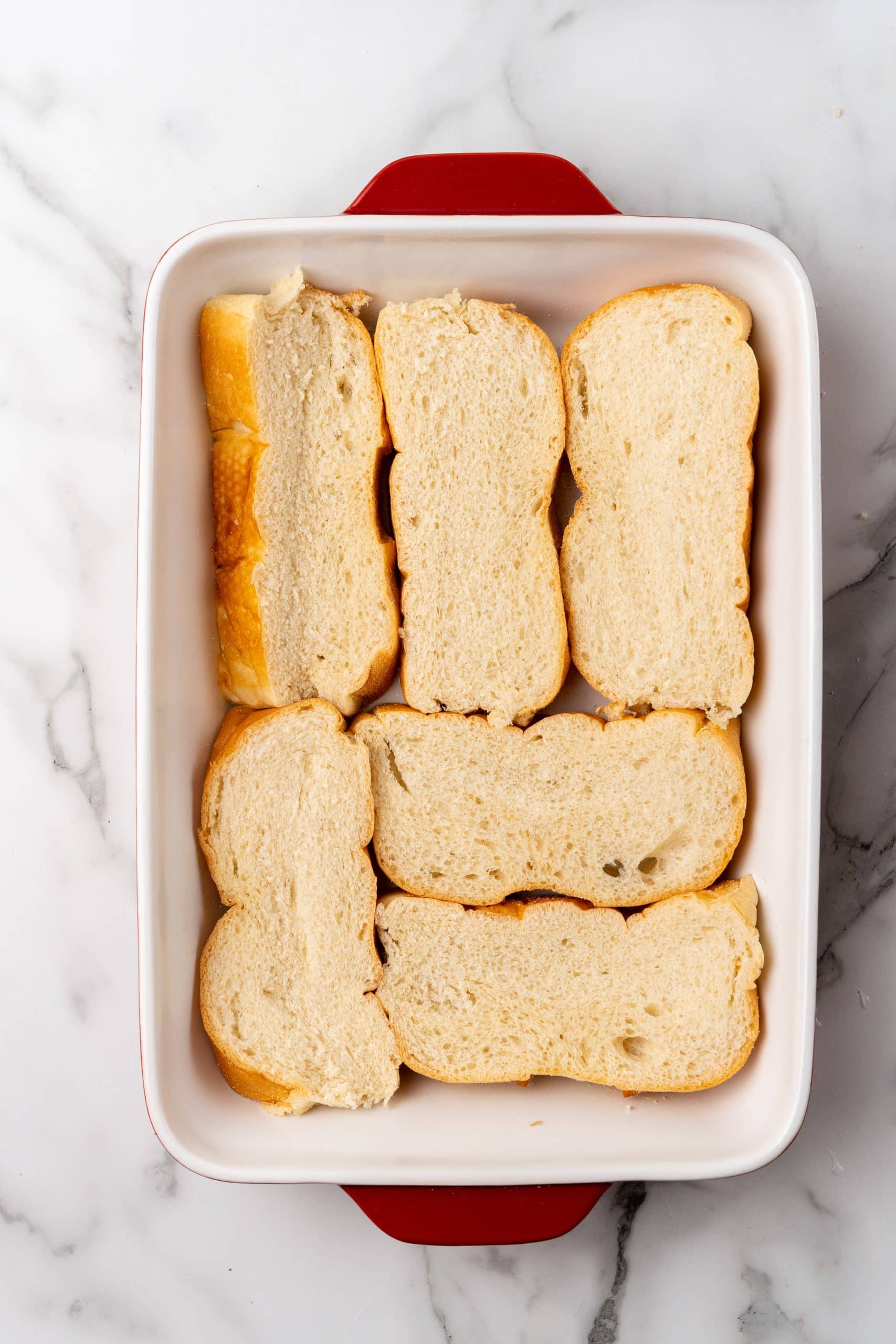 thick slices of Italian bread arranged in the bottom of a white 9x13" baking dish