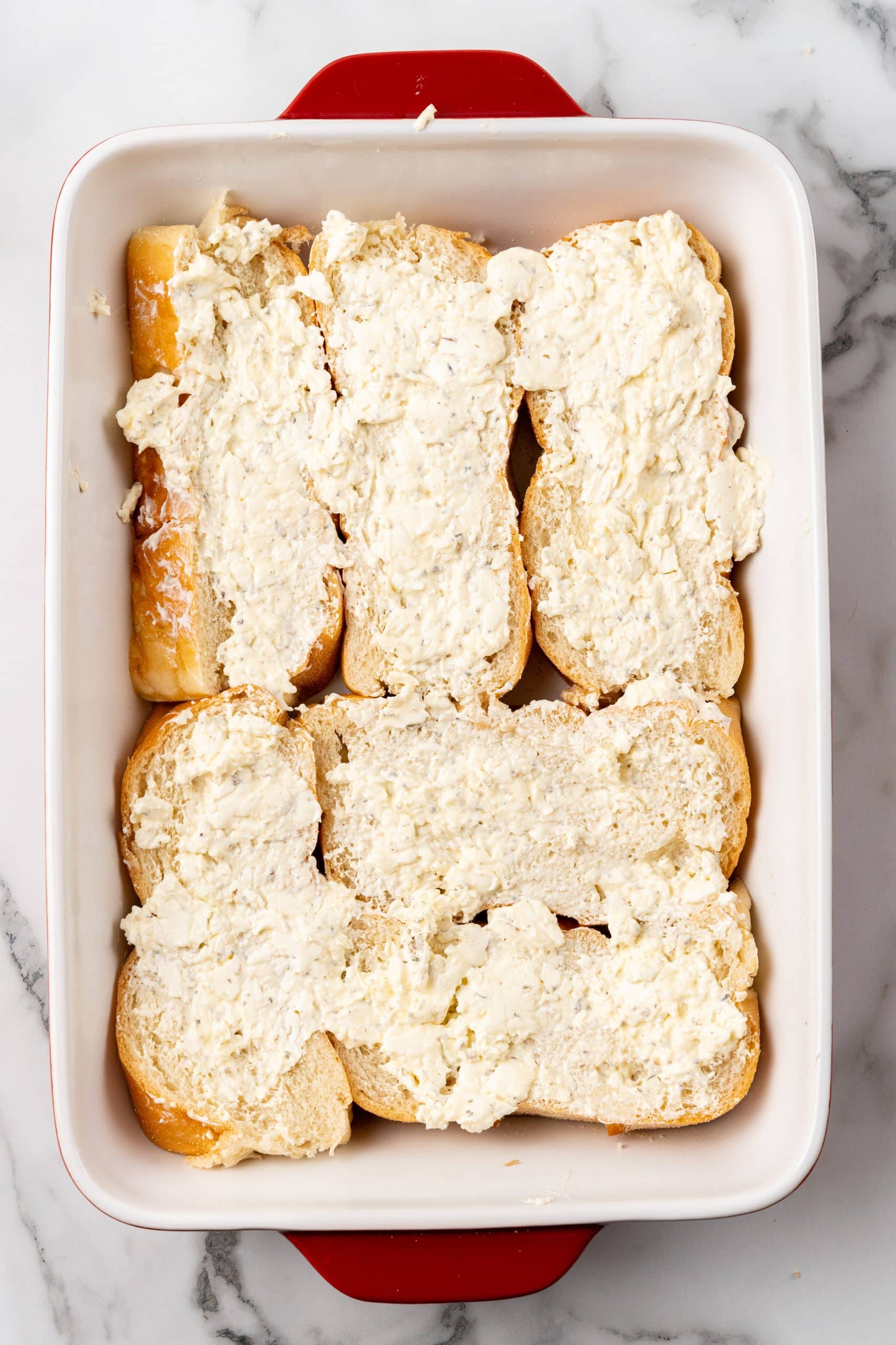 seasoned cream cheese mixture spread over thick slices of bread in a white baking dish