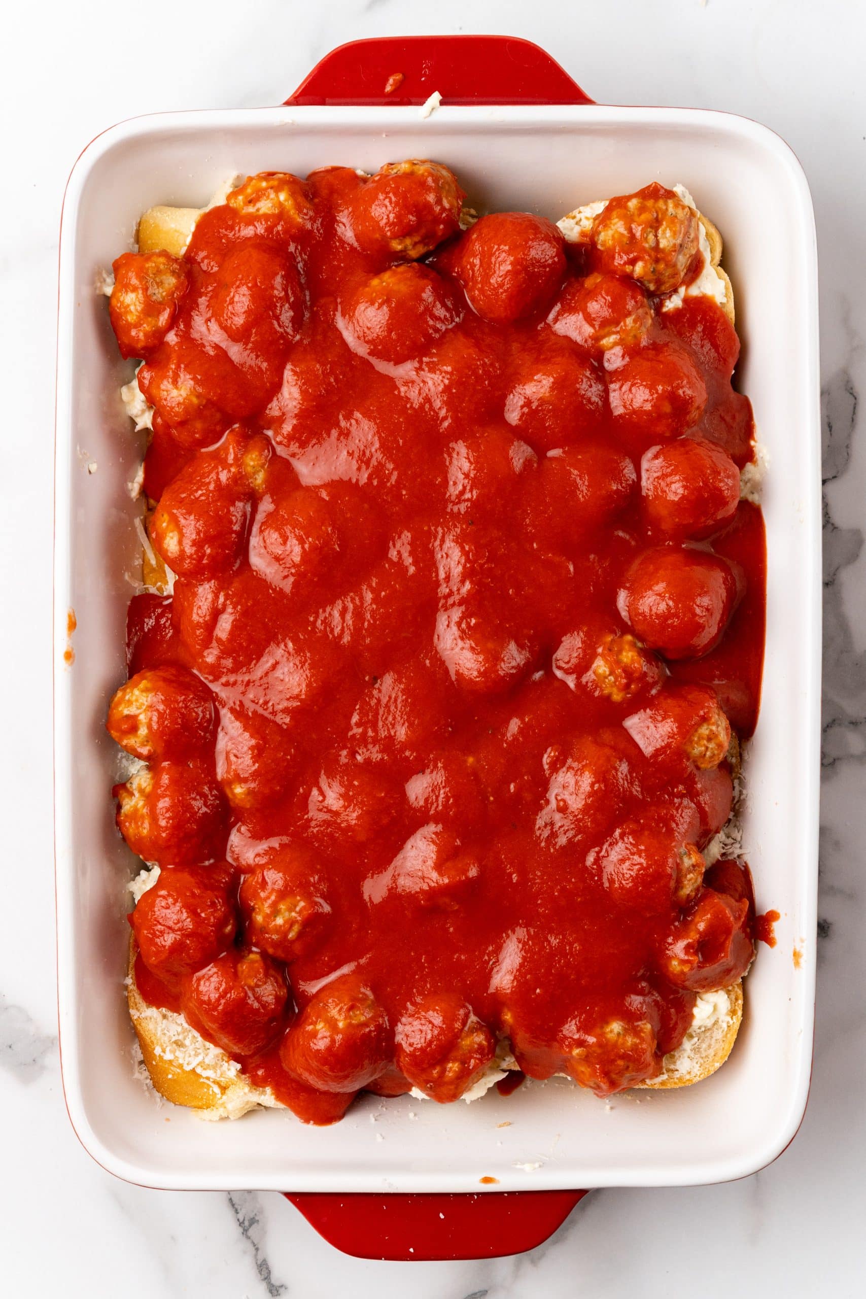 meatballs and sauce spread over slices of bread in a large baking dish