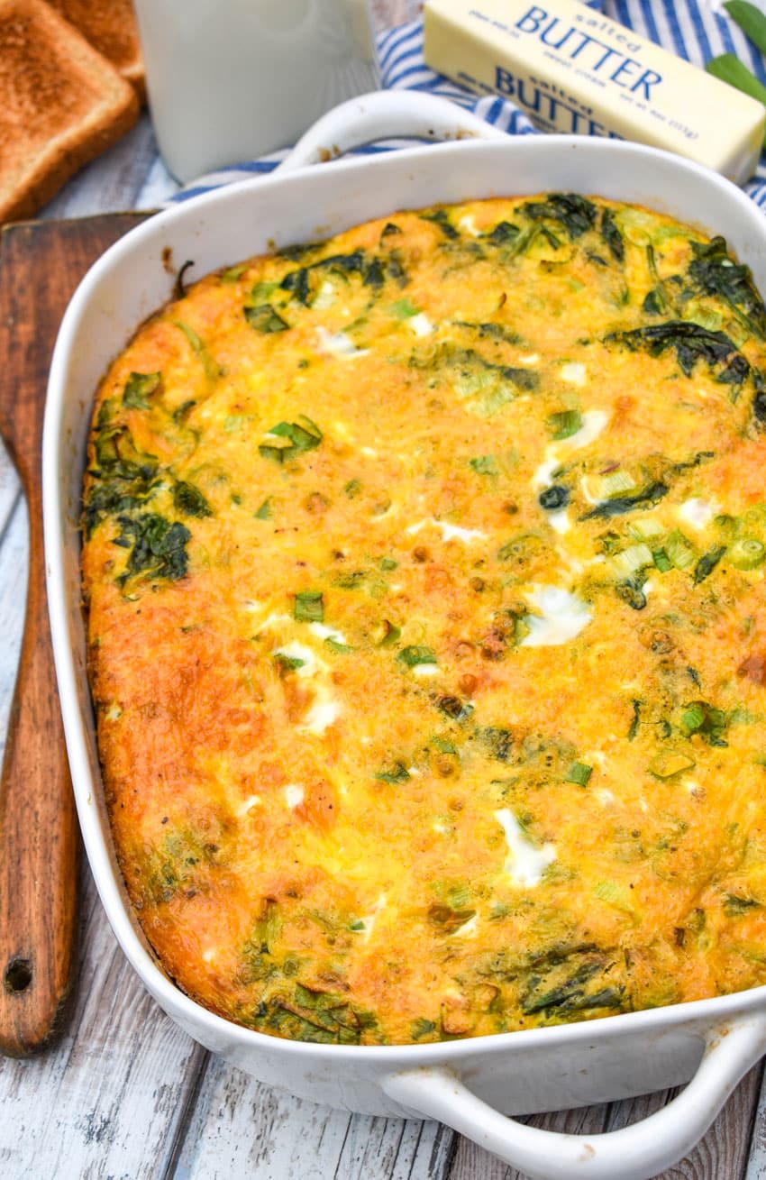 spinach cheddar egg bake in a white casserole dish