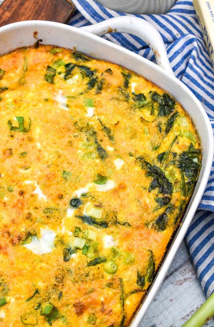 spinach cheddar egg bake in a white casserole dish