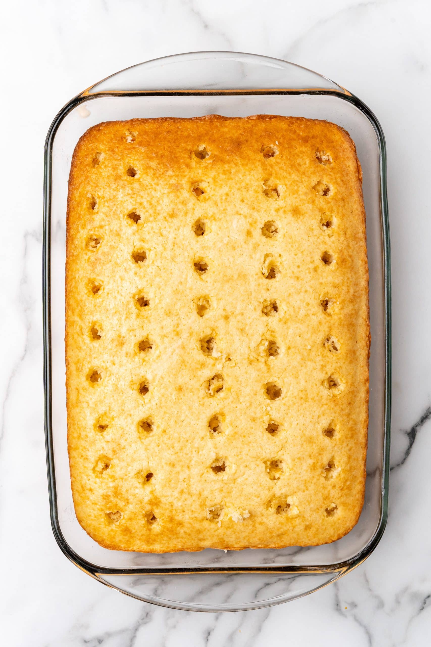 a baked cake with holes poked evenly out over the surface