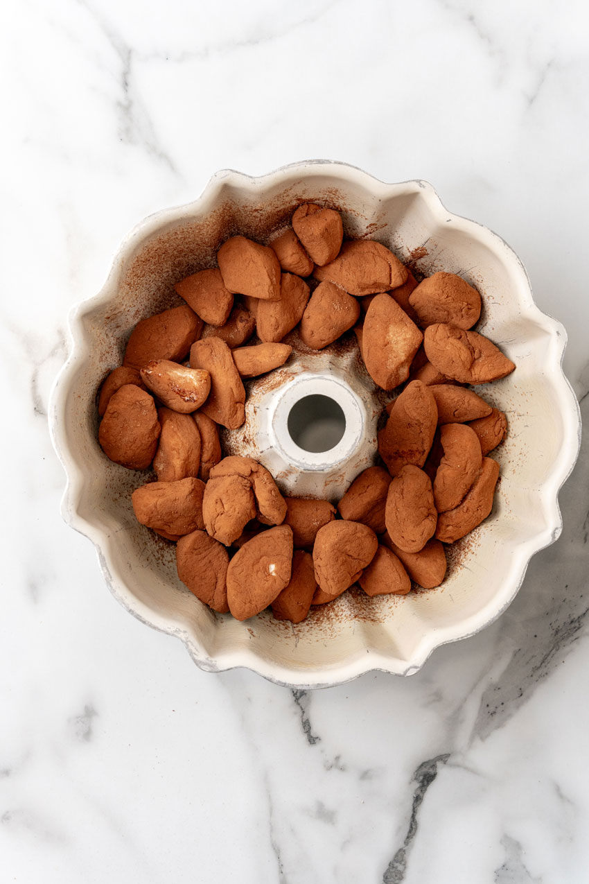 chocolate monkey bread biscuit pieces in a white bundt pan