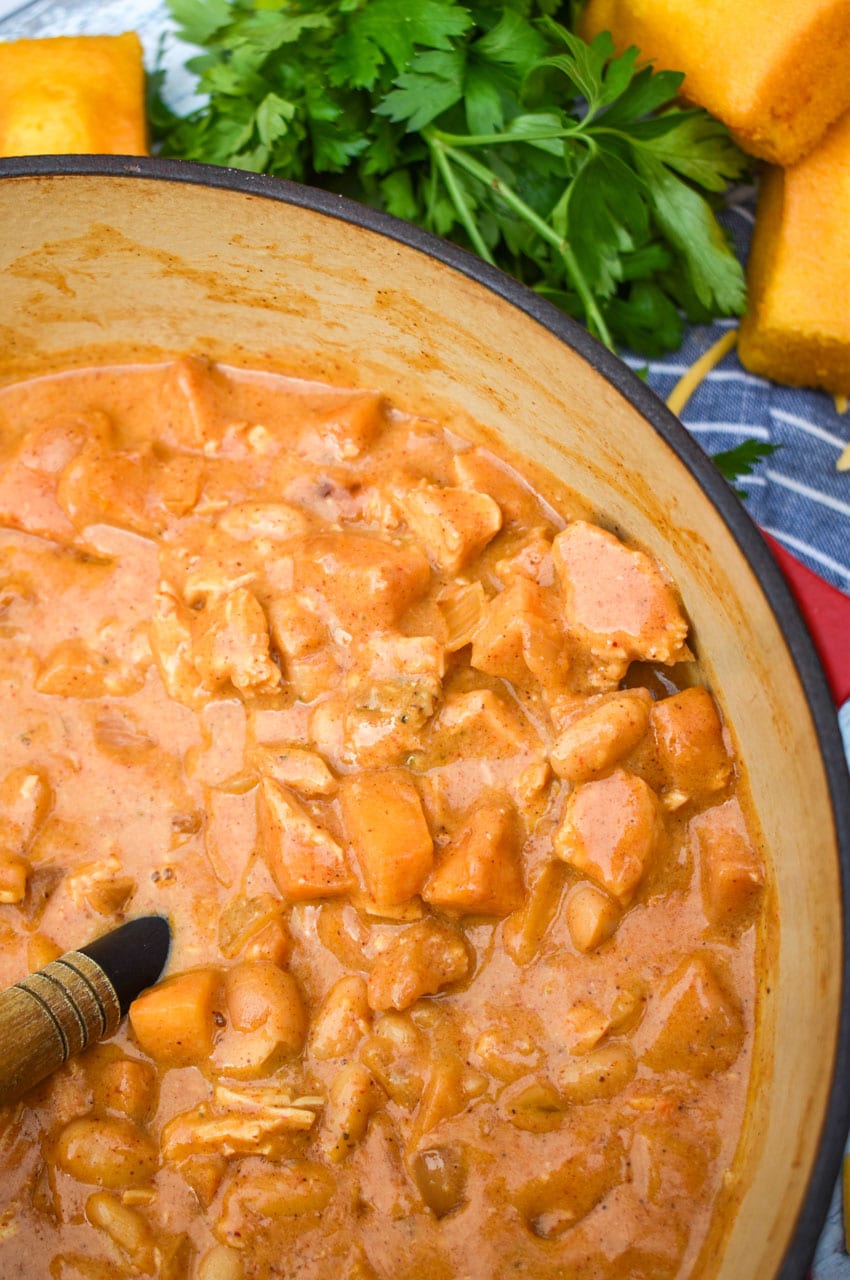 a wooden handled spatula in a pot filled with white cheddar chicken apple chili