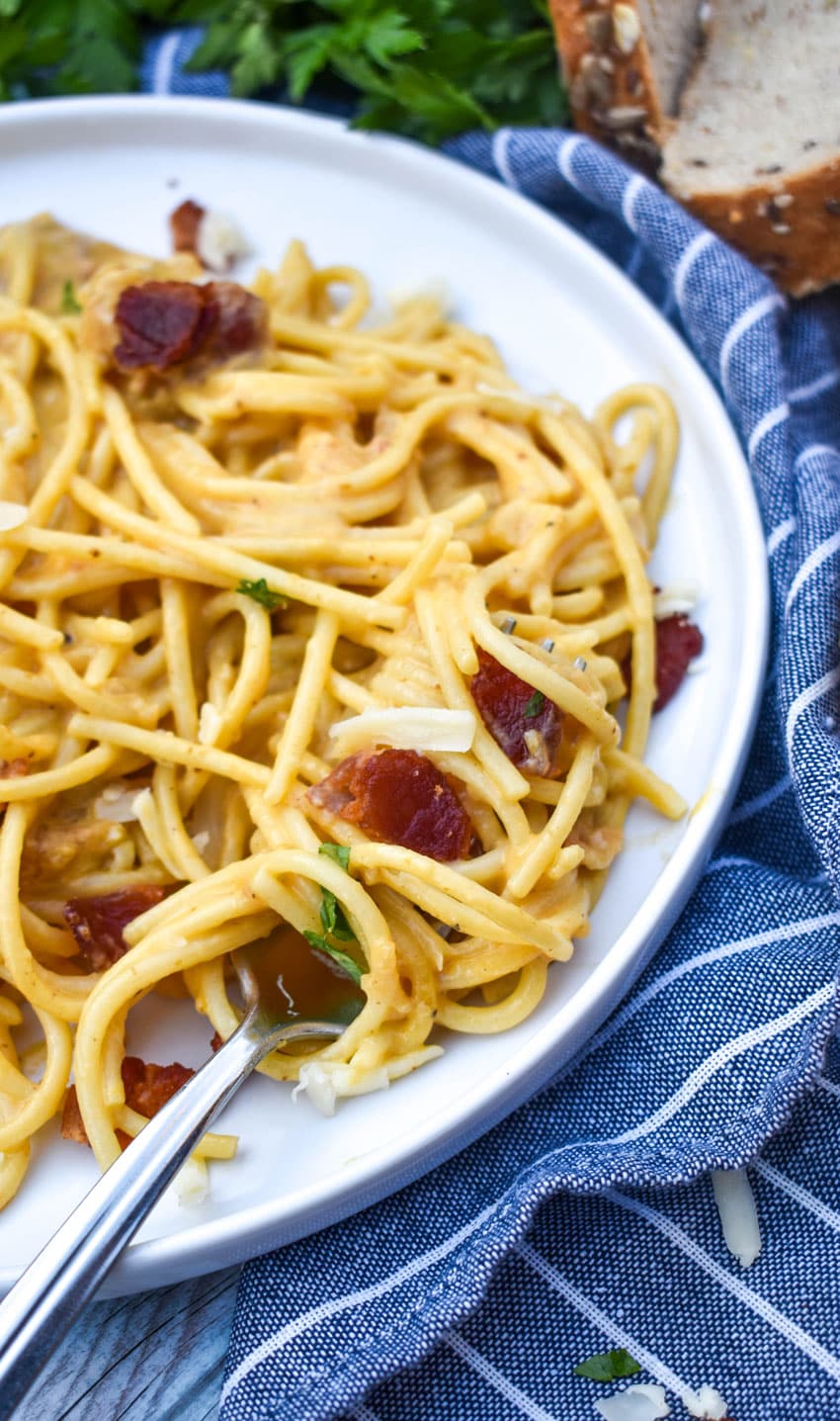 one pot creamy pumpkin pasta twired around a silver fork resting on a white dinner plate