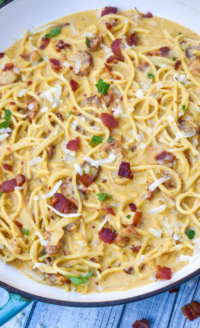 creamy pumpkin pasta topped with bacon in a blue skillet