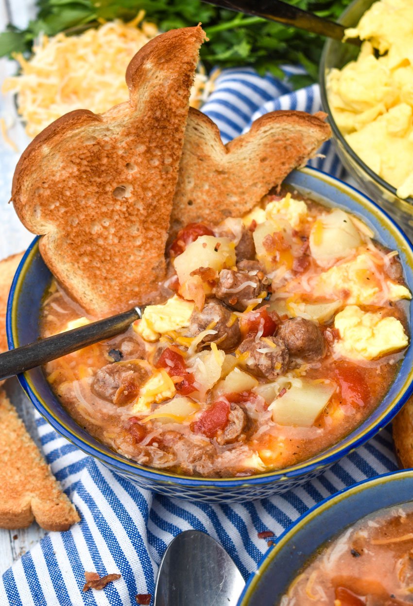 slow cooker breakfast soup in a blue bowl with a spoon and two halves of toast on the side