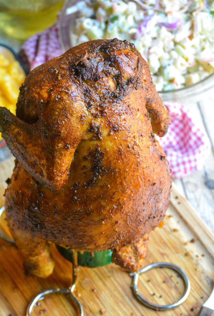 a smoked hard cider beer can chicken on a beer can stand resting on a wooden cutting board