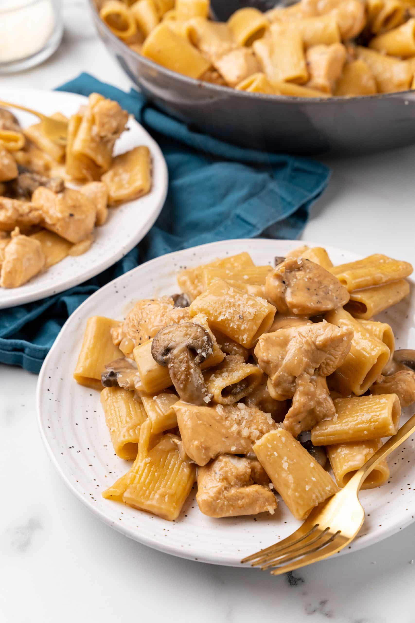 one pot chicken marsala pasta served on two white plates with a golden fork on the side