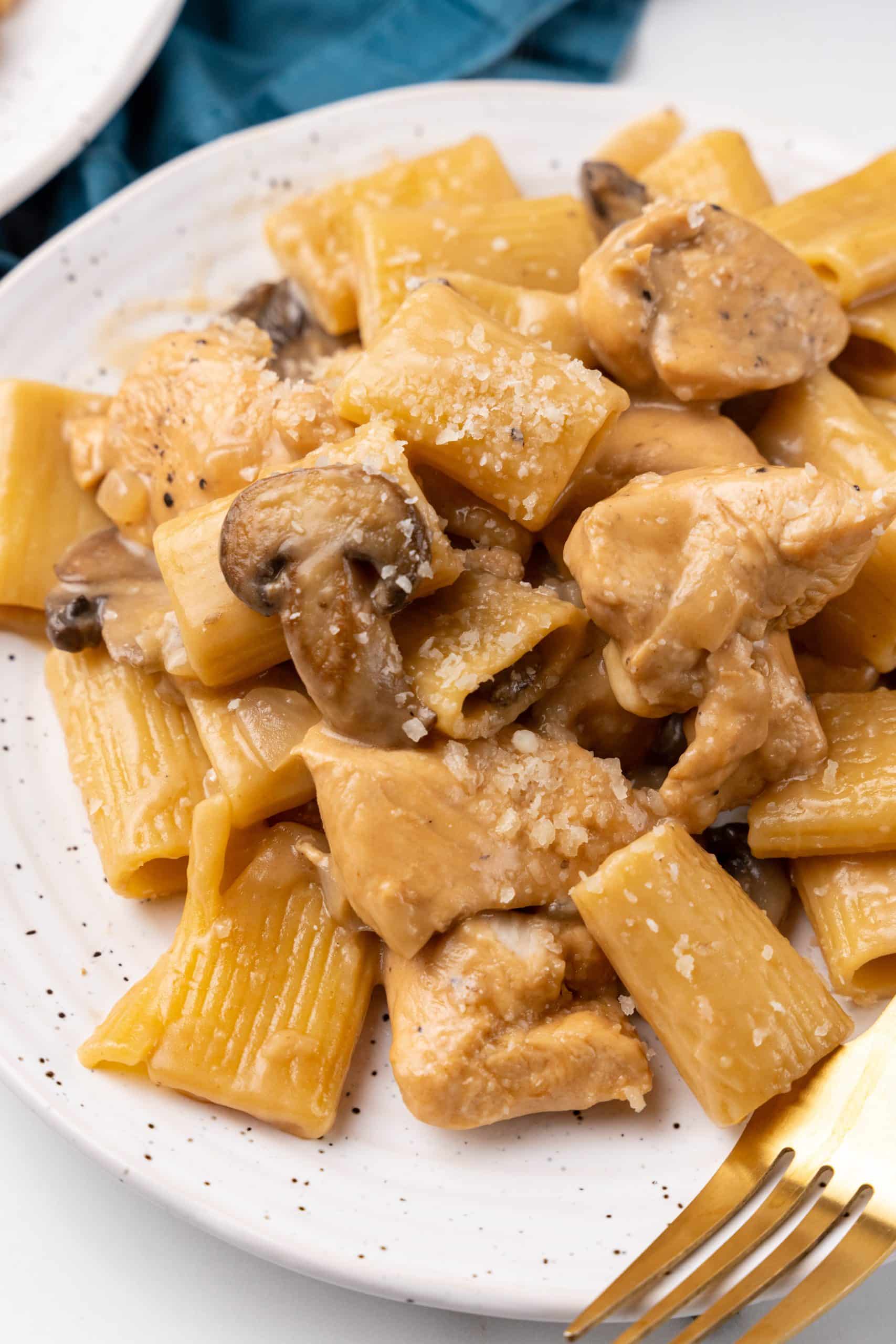 easy chicken marsala pasta on a white plate with a golden fork on the side