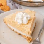 a slice of pumpkin ice cream pie on a white plate with a silver fork resting on the side
