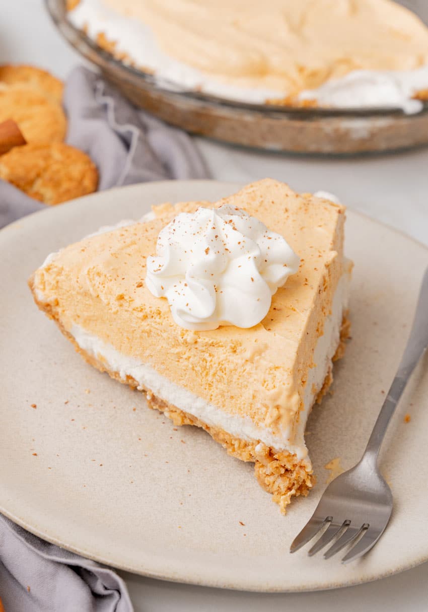 a slice of pumpkin ice cream pie on a white plate with a silver fork resting on the side