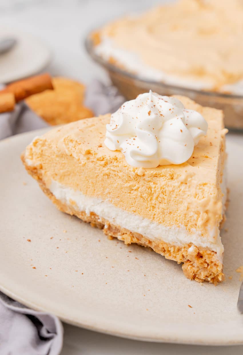 a slice of pumpkin ice cream pie on a white plate with a silver fork resting on the side