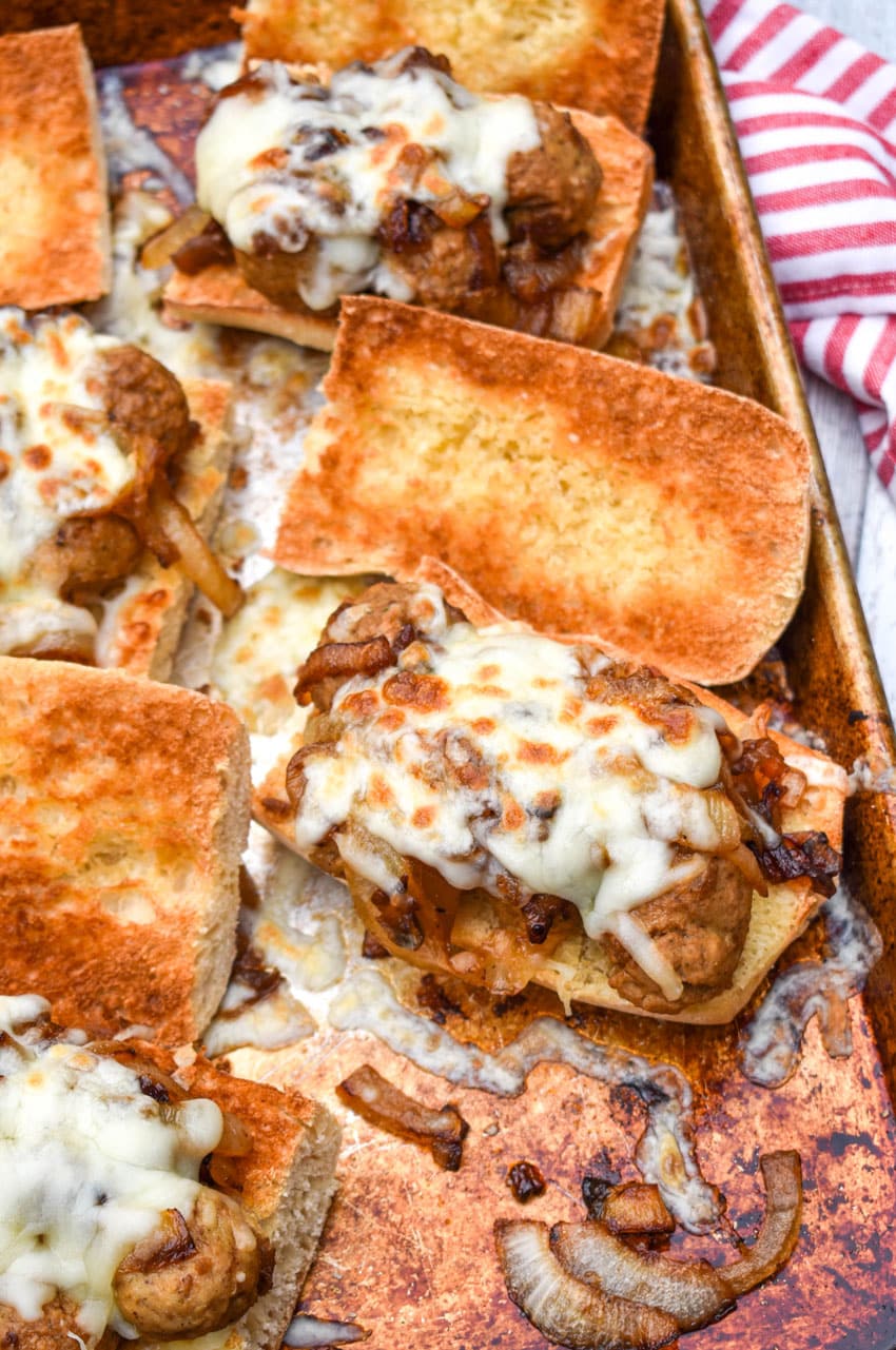 open face french onion meatball sub sandwiches on a metal sheet pan