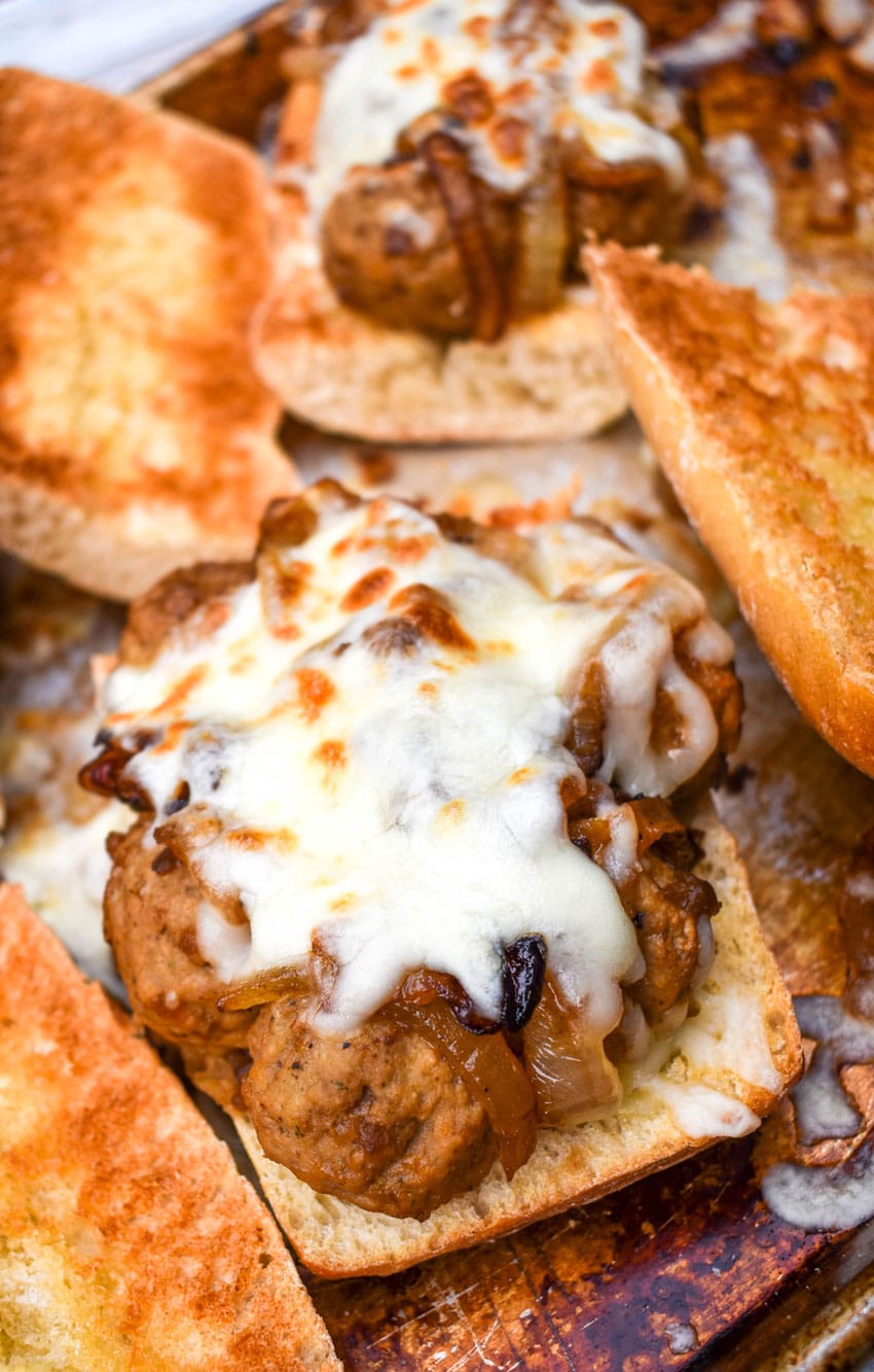 open face french onion meatball sub sandwiches on a metal sheet pan