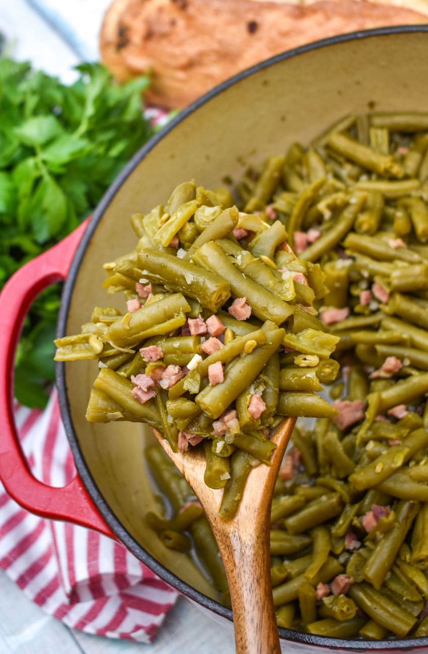 a wooden spoon holding up a scoop of grandma's canned green beans