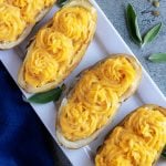 FOUR PUMPKIN PARMESAN TWICE BAKED POTATOES ON A WHITE SERVING PLATTER WITH FRESH SAGE LEAVES FOR GARNISH